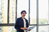 Portrait man using laptop at urban apartment window