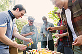 Male friends standing around barbecue grill
