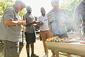 Male friends drinking beer around barbecue grill