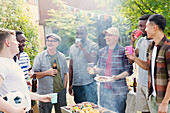 Male friends drinking beer around barbecue grill