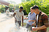Young men barbecuing in backyard