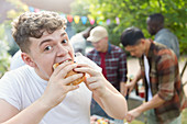 Portrait hungry teenage boy eating hamburger