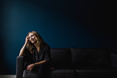 Happy woman sitting on sofa, looking away