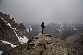 Female hiker on top of craggy, foggy mountain Canada