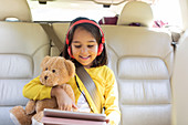 Smiling girl using tablet in back seat of car
