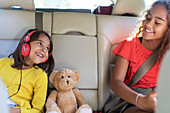 Sisters and teddy bear riding in back seat of car