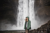 Smiling hiker in rain jacket at waterfall, Canada