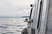 Cute dog looking out boat window onto river, Canada