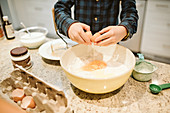 Boy baking, cracking egg into bowl