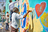 Senior man painting mural on urban wall