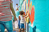 Girl volunteer painting vibrant mural on wall