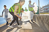 Woman volunteer picking up plastic litter on boardwalk