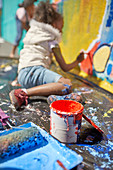 Girl painting mural behind paint can
