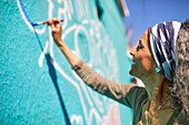 Senior woman painting mural on wall