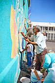 Community volunteers painting vibrant mural on urban wall