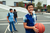 Portrait tween boy playing basketball in schoolyard