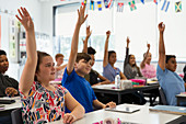 Eager school students with hands raised