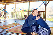 Happy mother and daughter hugging on yoga mats in hut