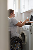 Young woman in wheelchair preparing tea