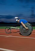 Determined paraplegic athlete in wheelchair race at night