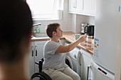 Young woman in wheelchair preparing tea