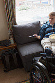 Young woman watching TV with feet up on wheelchair