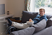 Portrait woman watching TV, feet up on wheelchair