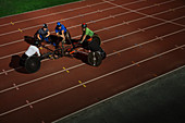 Paraplegic athletes huddling, training for wheelchair race