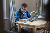 Focused woman in wheelchair using laptop