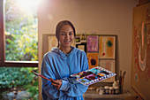 Portrait smiling female artist painting in art studio