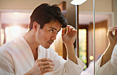 Man checking hair in bathroom mirror