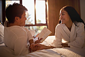 Couple in bathrobes reading book in bed