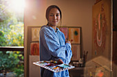 Portrait confident female artist painting in art studio