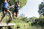 Playful mother and daughter jumping into river