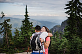 Happy couple hiking, hugging on mountain, Canada