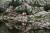 Portrait couple hiking, resting at rocky lake, Canada
