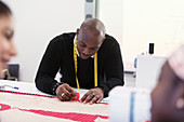 Focused male fashion designer marking sewing pattern