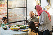 Mother in hijab serving dinner to family