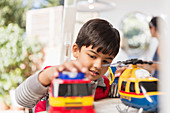 Boy playing with toy helicopter and fire engine