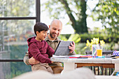 Father and son using digital tablet at table