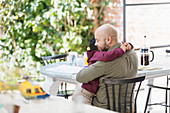 Affectionate father and son hugging at table