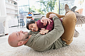 Playful father and son hugging on floor