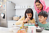 Mother in hijab baking with children in kitchen