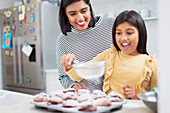 Mother and daughter baking muffins in kitchen