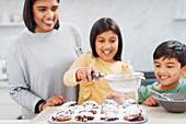 Mother and children baking muffins in kitchen