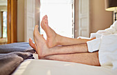 Barefoot couple relaxing on hotel bed