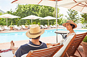 Couple relaxing on lounge chairs at resort poolside