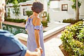 Couple holding hands, walking at poolside