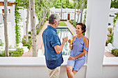 Mature couple drinking mimosas on hotel balcony