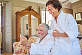 Happy mature couple in spa bathrobes drinking coffee